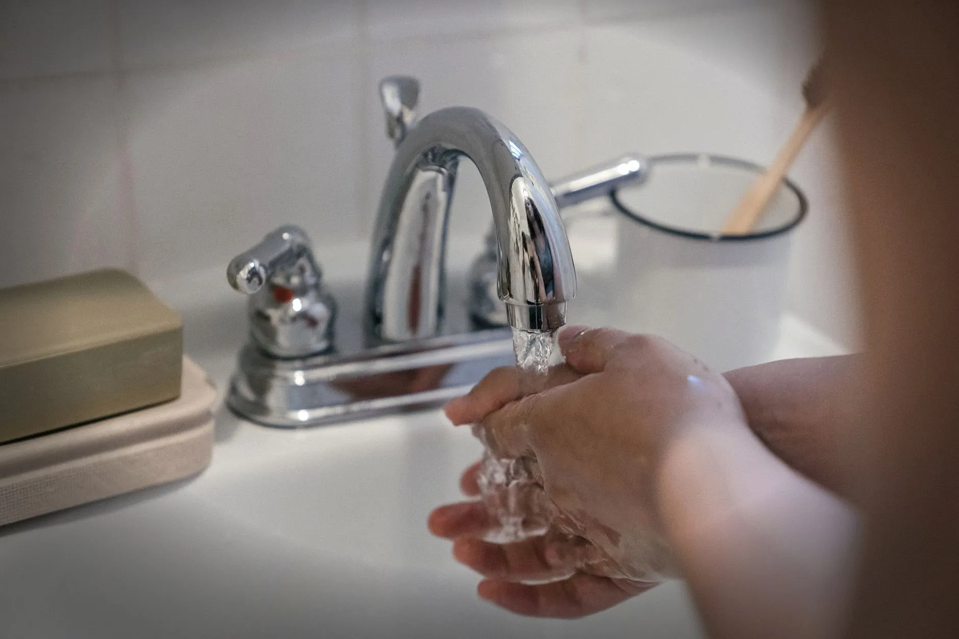 Hands washing under a faucet with running water, emphasizing hygiene and cleanliness.