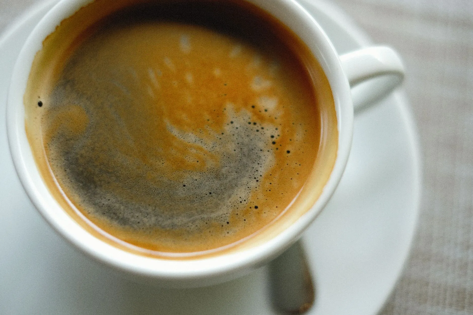 A detailed close-up shot of a steaming cup of coffee showcasing rich, swirling crema.