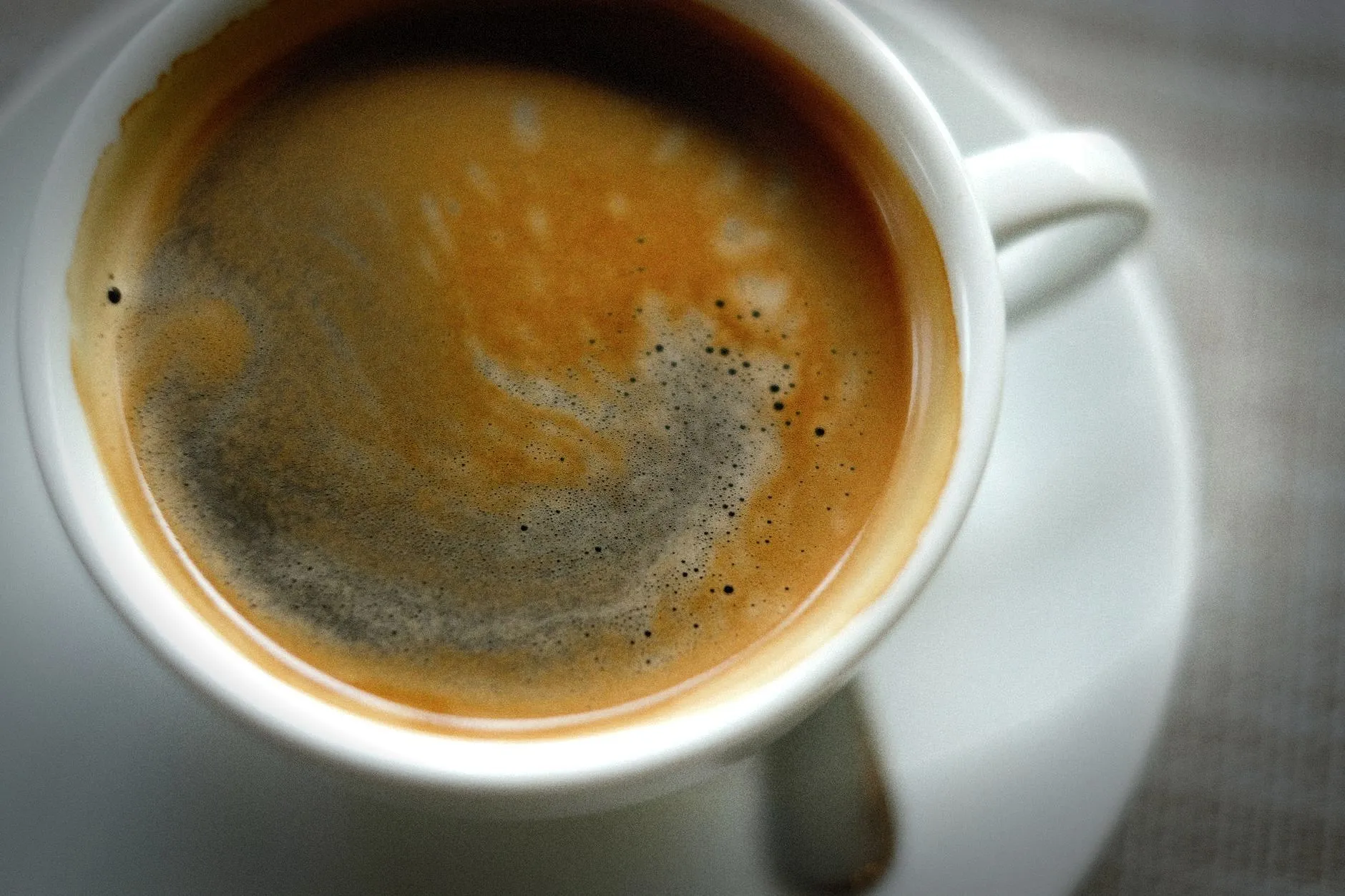 A detailed close-up shot of a steaming cup of coffee showcasing rich, swirling crema.