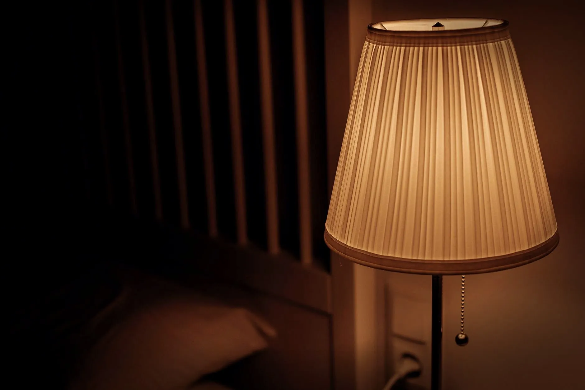 A dimly lit bedside lamp creating a warm and cozy atmosphere in a bedroom setting.