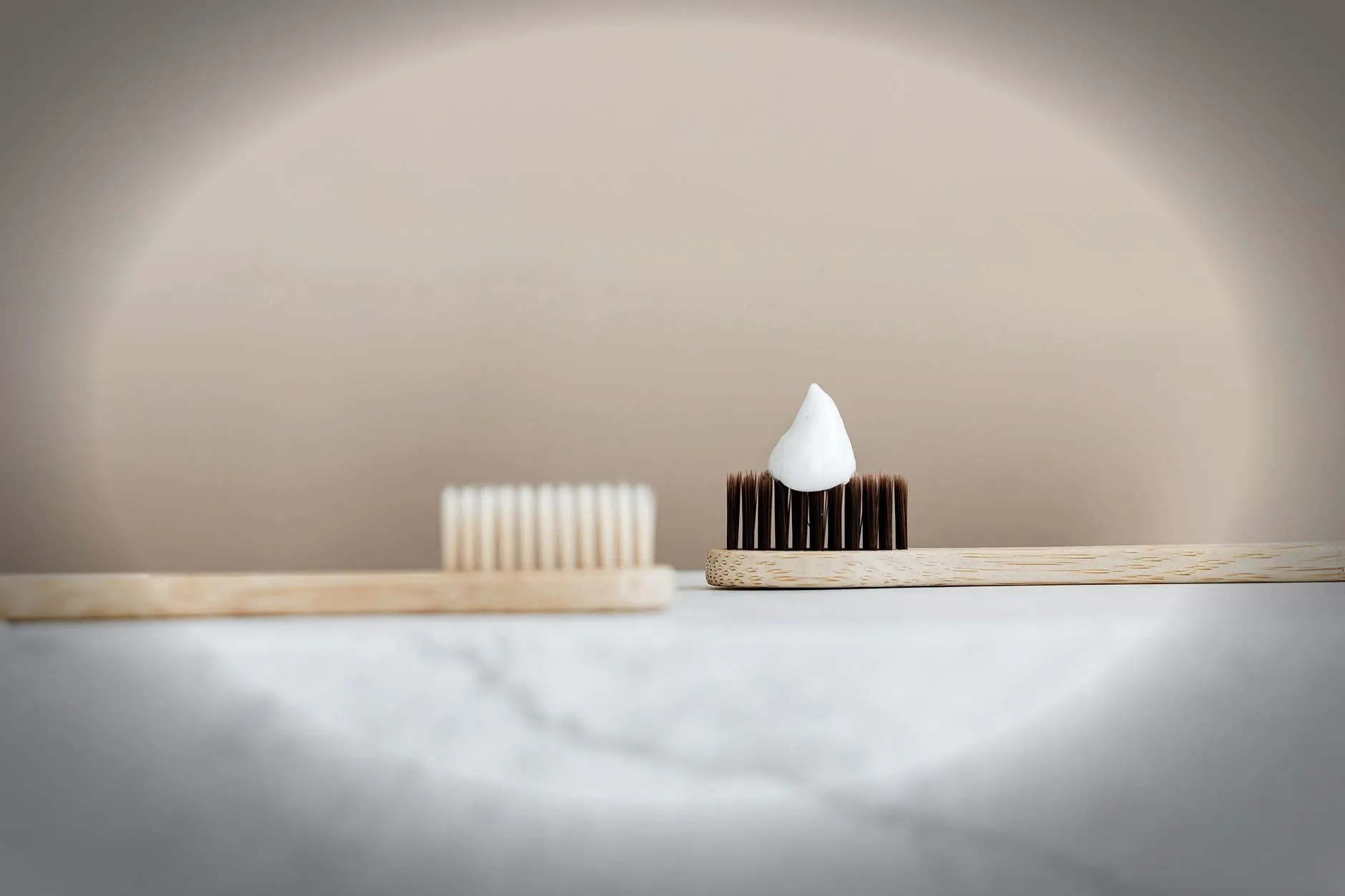Close-up of a bamboo toothbrush with toothpaste in a minimalist setting.